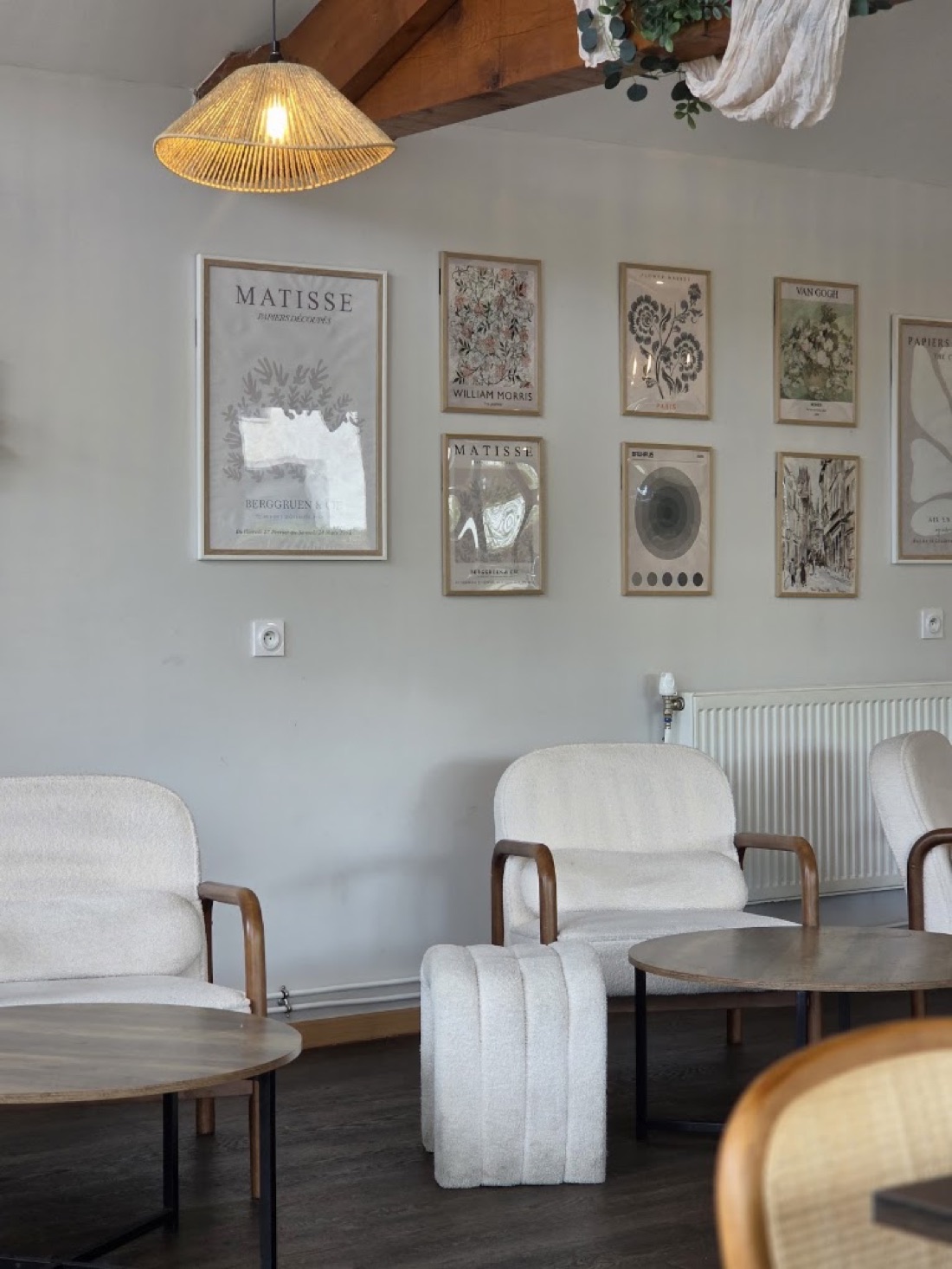 Salle de L'Éclat Gourmand, fauteuils bouclette blancs et mur de cadres botaniques