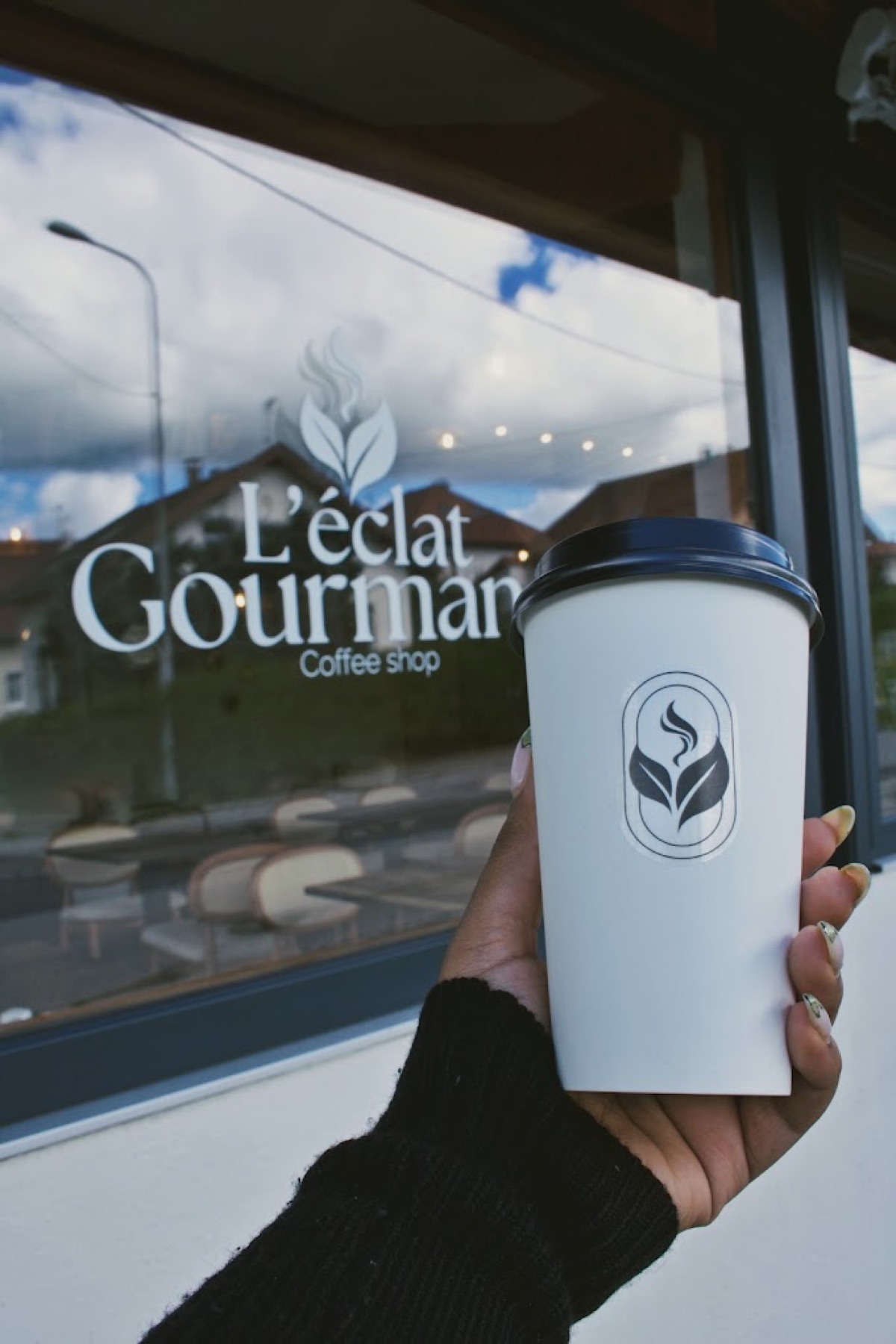Devanture de L'Éclat Gourmand au coucher du soleil, gobelet à emporter à la main